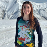 Person wearing a colorful patterned shirt standing in a snowy landscape with mountains.